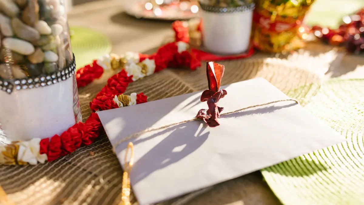 A white envelope tied with string on a festive table with red and white flower garlands