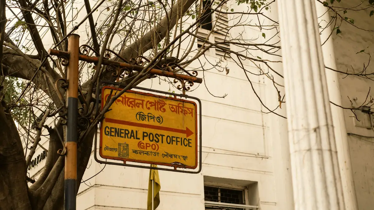 The bilingual sign of the General Post Office in Kolkata, in Bengali and English, beside the building's columns