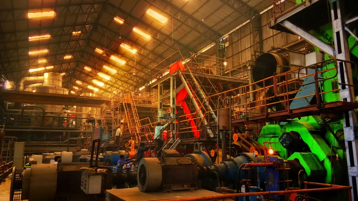 Large machines, walkways and rows of overhead lights inside a factory shed