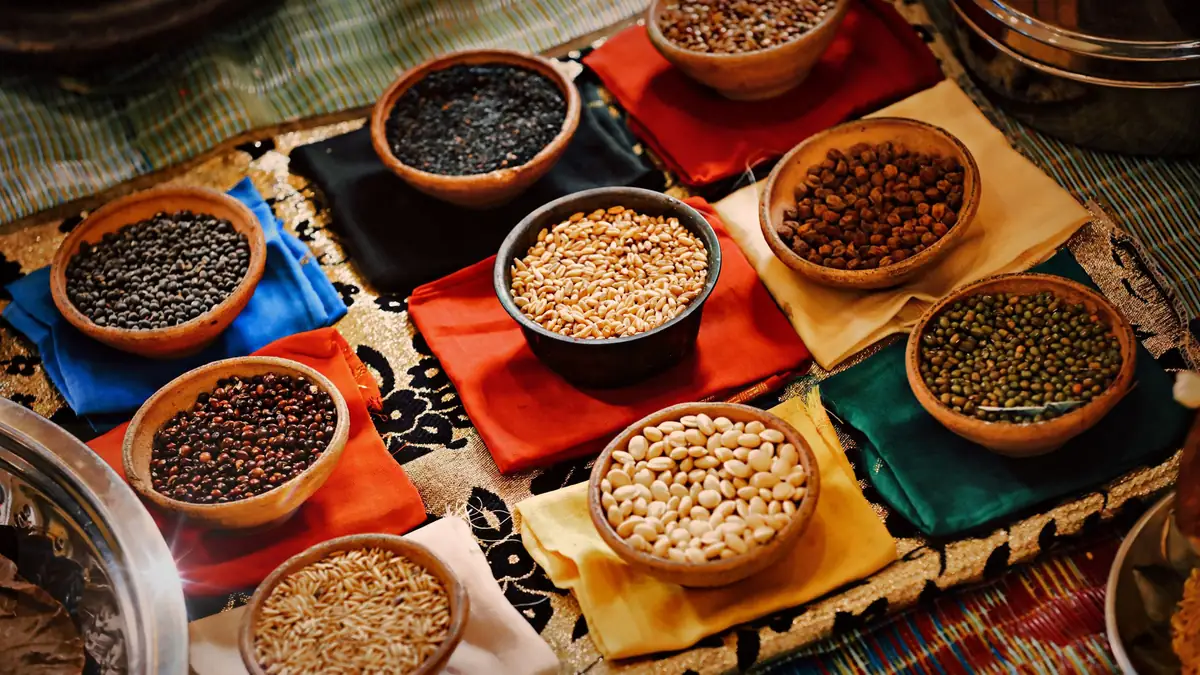 Terracotta bowls of millets, pulses and grains set out on coloured cloths