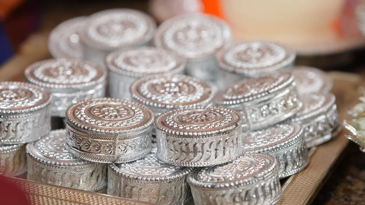 A tray stacked with ornate silver-finish round boxes of the kind given as wedding gifts